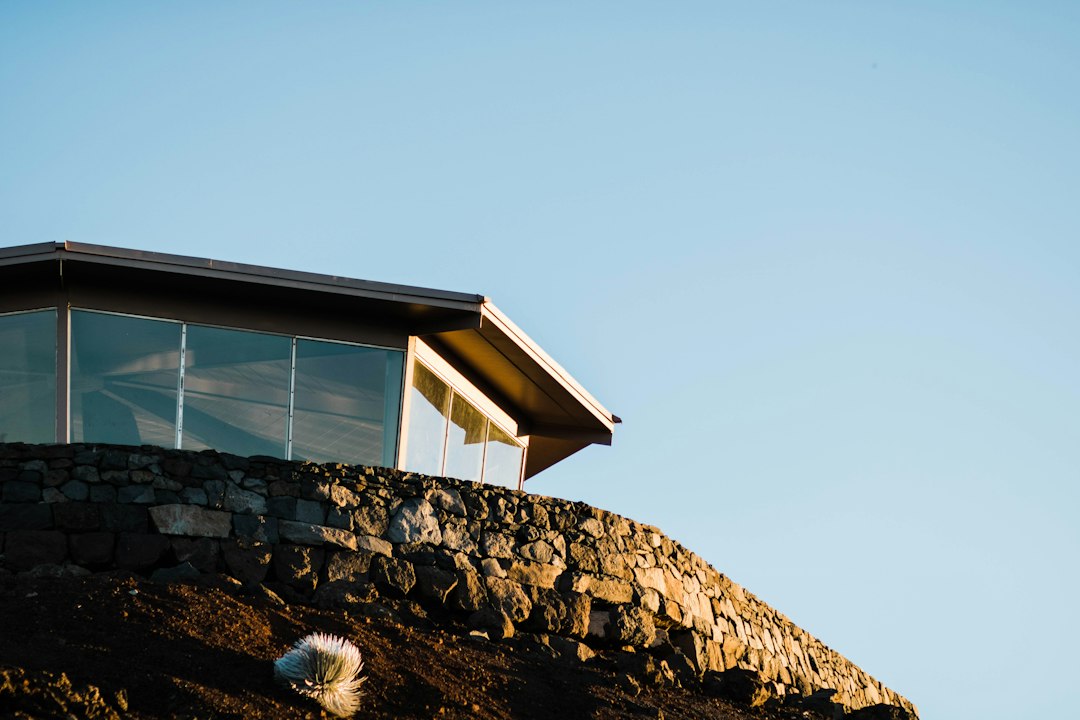 The stunning exterior of a modern luxury home with large windows and clean lines, set against a backdrop of the Aspen mountains on a clear, sunny day.